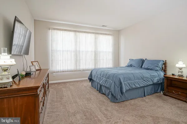a spacious bedroom with a large bed and a flat tv screen on a dresser