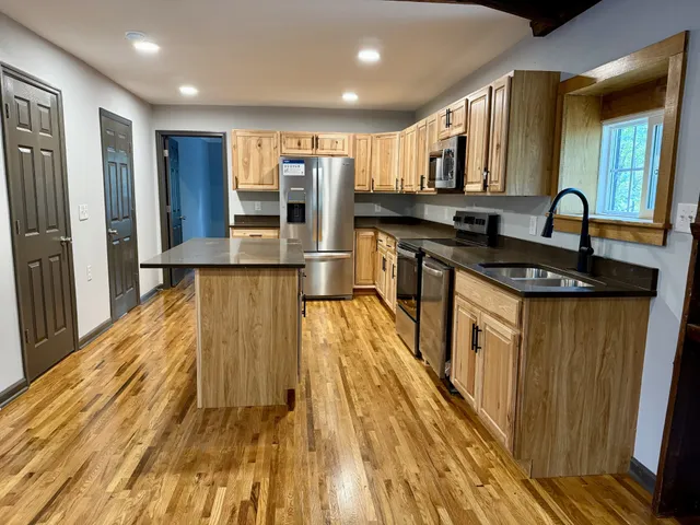 a kitchen with stainless steel appliances granite countertop a sink and wooden cabinets
