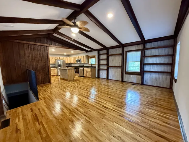 a view of empty room with wooden floor and fan