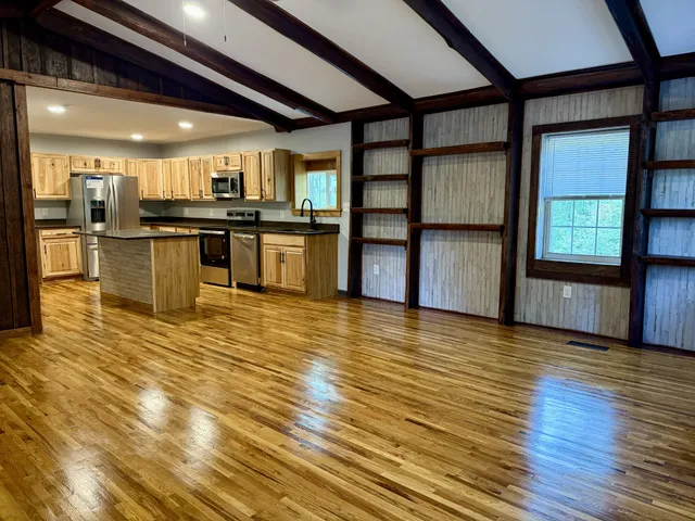 a view of a kitchen with kitchen island a sink wooden floor and stainless steel appliances