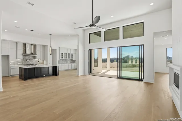 a view of an empty room with kitchen and a window