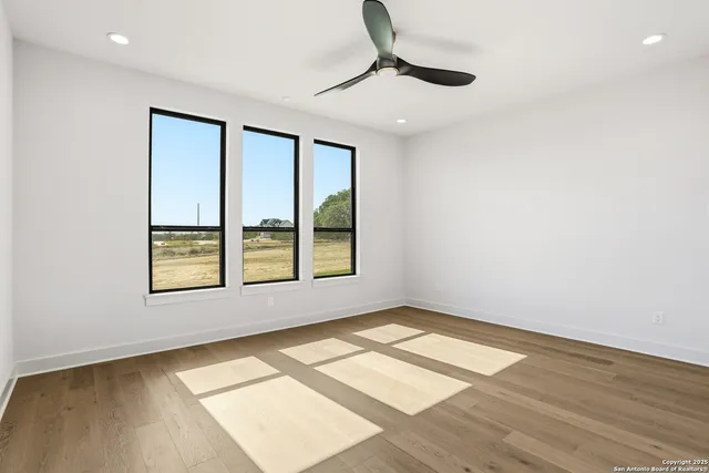 an empty room with wooden floor and windows