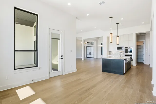 a large room with lot of kitchen furniture and wooden floor