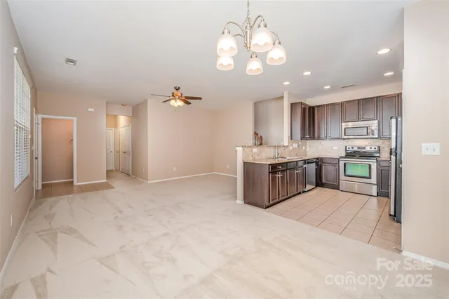 a kitchen with stainless steel appliances granite countertop a refrigerator a sink dishwasher a stove and a refrigerator with wooden floor