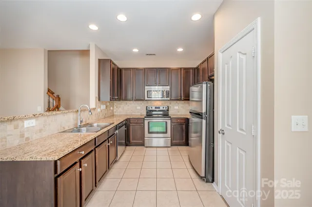 a large kitchen with stainless steel appliances granite countertop a refrigerator and a sink