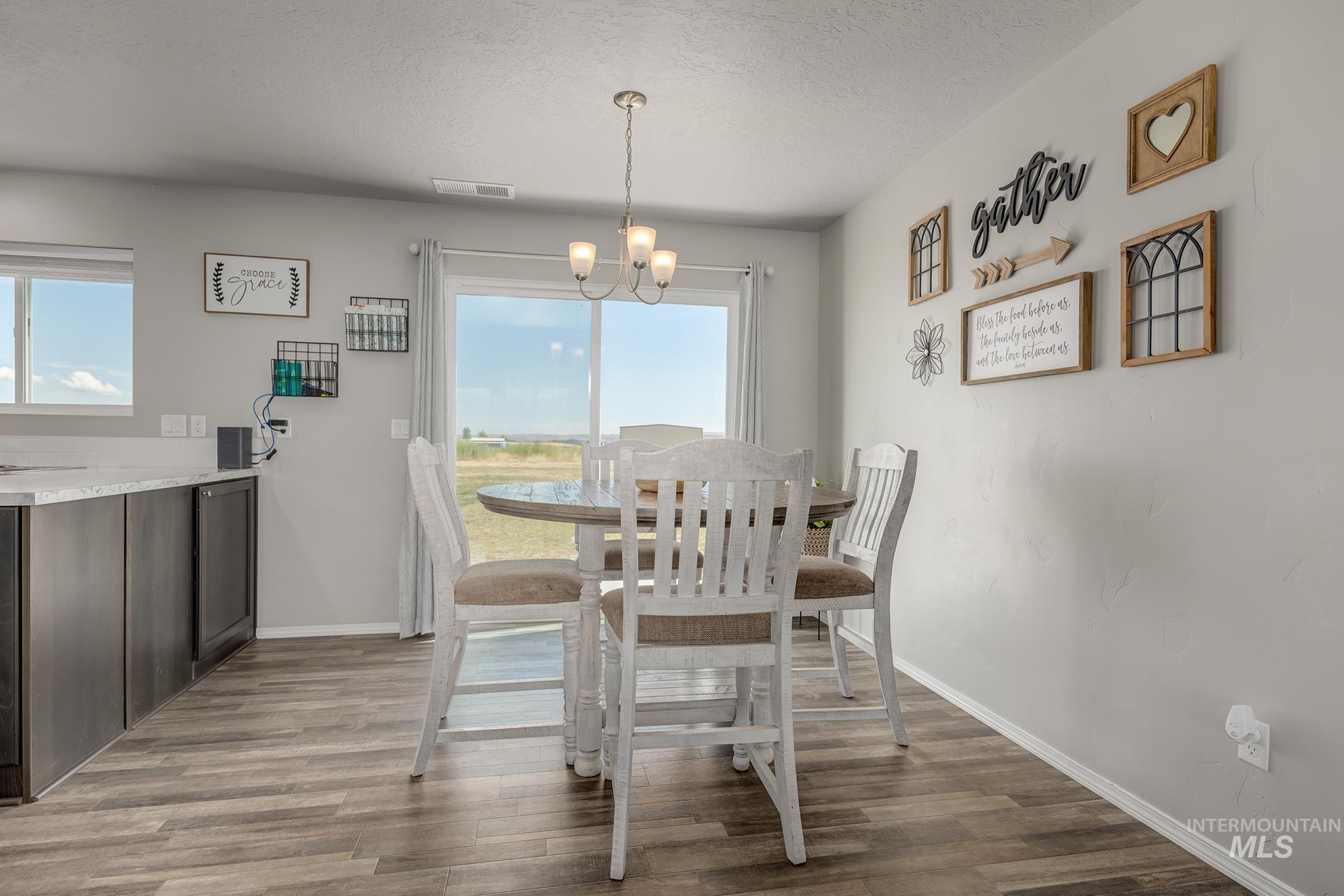 1049 Price Road Weiser, ID 83672 - Photo 6 of 47 Open-concept dining area featuring wood-finish flooring, a contemporary chandelier, and direct access to the outdoor space via sliding glass doors