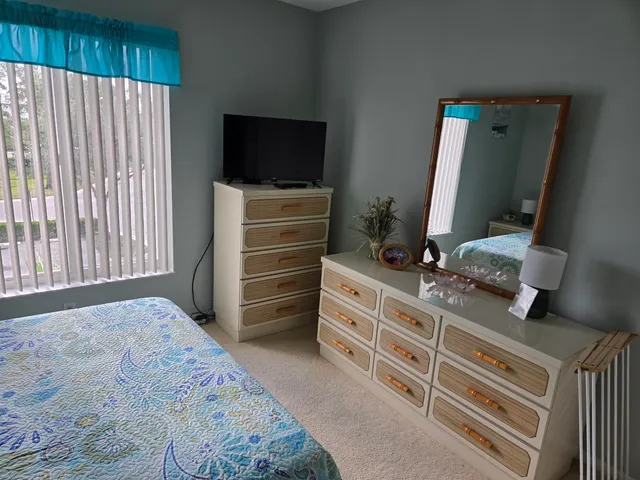 a bedroom with a bed and a flat tv screen on dresser