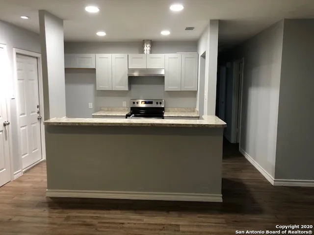 a kitchen with kitchen island granite countertop a sink and a refrigerator