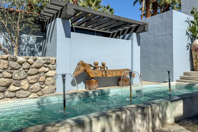 a view of swimming pool with a bench and trees in the background