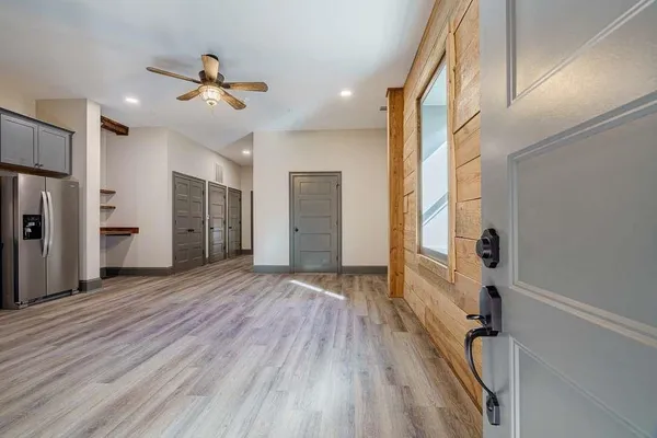 a view of empty room with wooden floor and fan