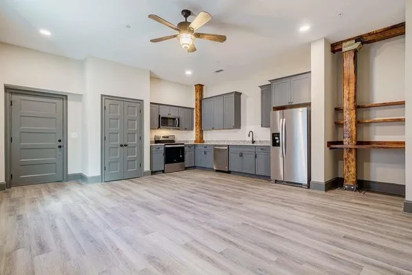 a view of kitchen with stainless steel appliances wooden floor and window