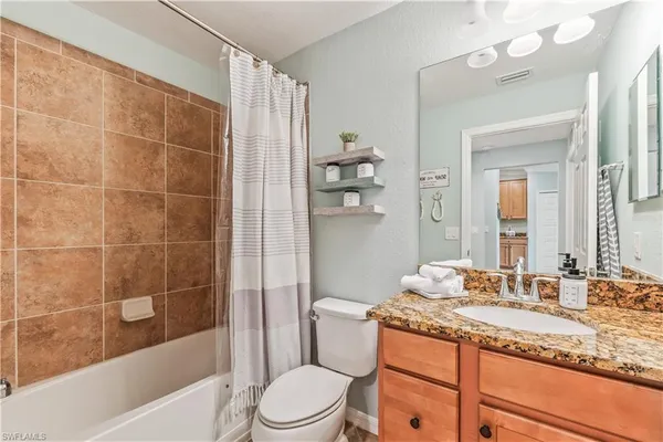 a bathroom with a granite countertop sink a toilet a mirror and bathtub