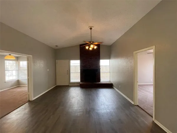 a big room with wooden floor fireplace and windows