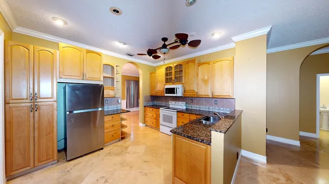 a kitchen with stainless steel appliances granite countertop a refrigerator a stove and a sink with wooden floor