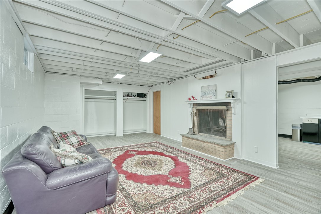 255 Fairport Road East Rochester, NY 14445 - Photo 22 of 26 Exposed beams overhead and a brick fireplace create a cozy atmosphere in this finished lower level.
