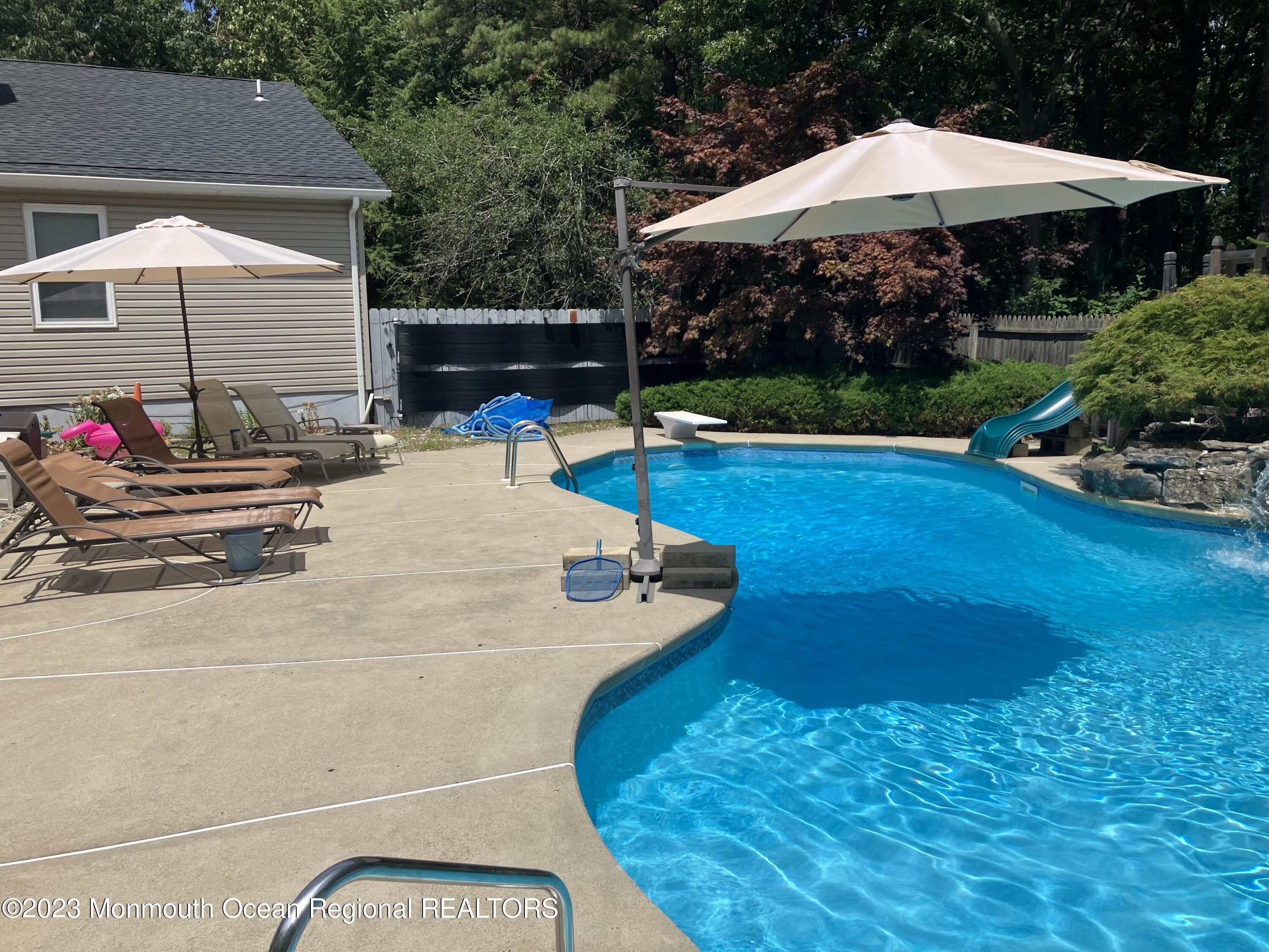 310 Easy Street Howell, NJ 07731 - Photo 33 of 45 a backyard of a house with table and chairs under an umbrella