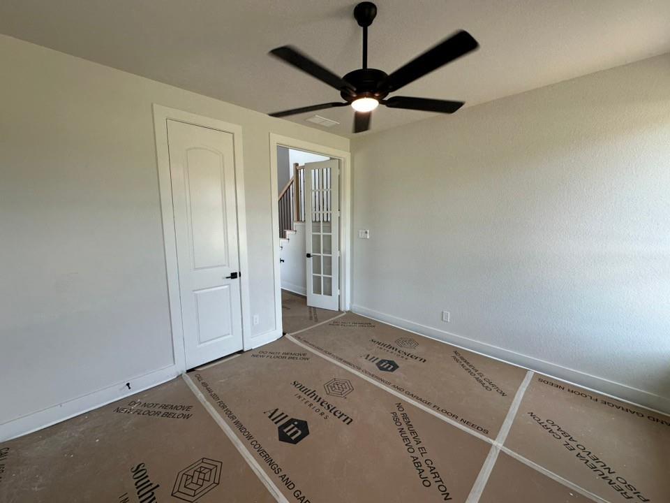 605 Brown Road Leonard, TX 75452 - Photo 5 of 25 Spacious room featuring a contemporary ceiling fan with integrated lighting, a white paneled door, and a doorway opening to a staircase with wood handrails and black balusters