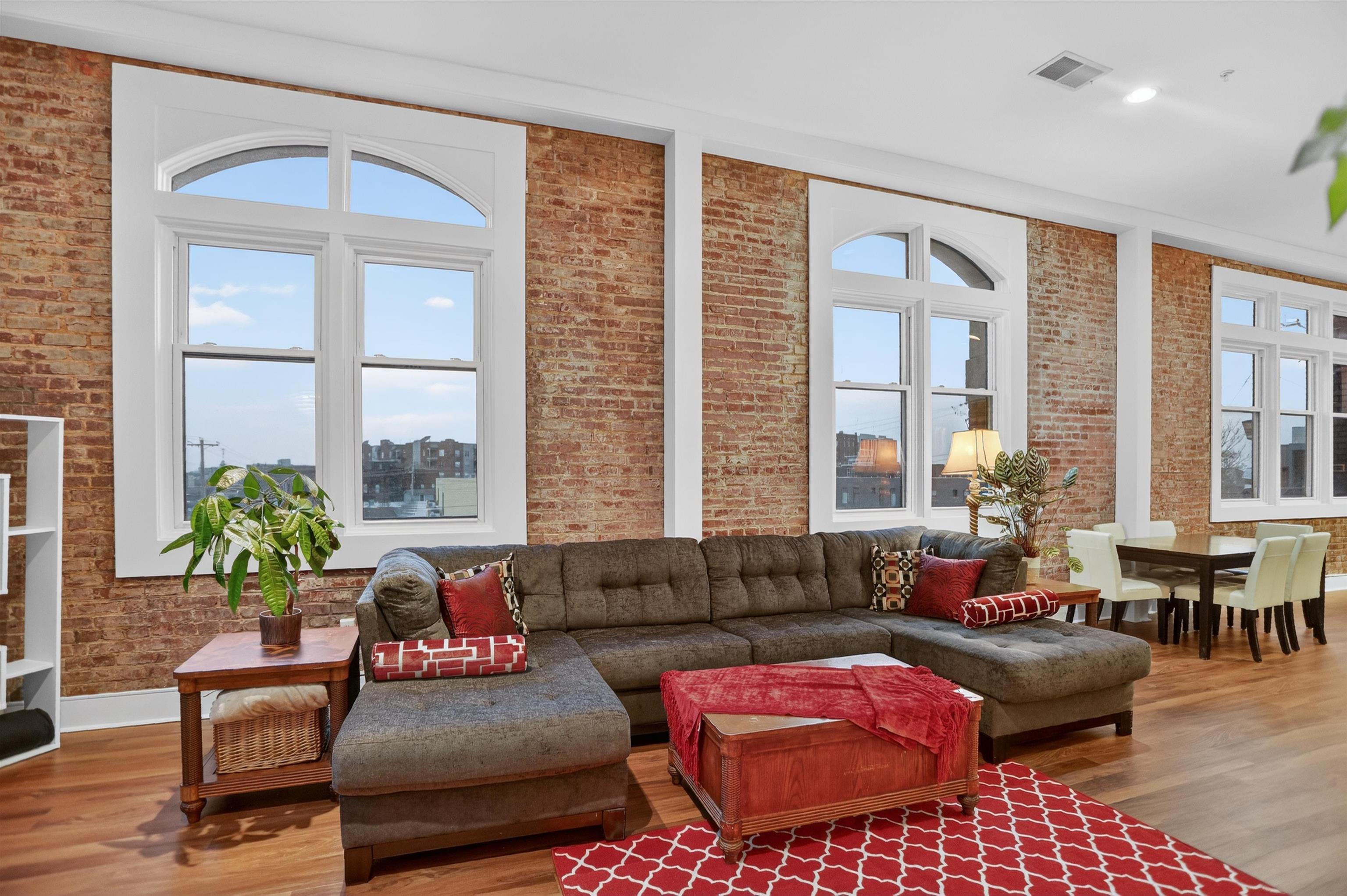 435 South Front Street, Unit 307 Memphis, TN 38103 - Photo 14 of 40 Living area featuring brick wall, wood finished floors, healthy amount of natural light, and a towering ceiling