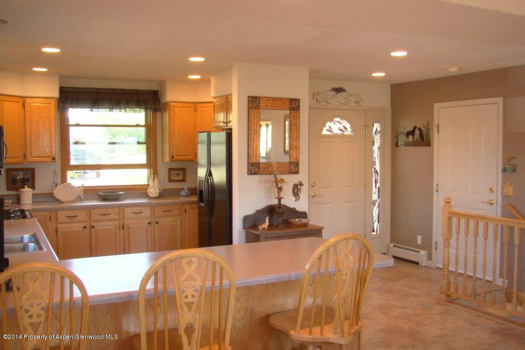 1001 Arnold Court Rifle, CO 81650 - Photo 10 of 39 a large kitchen with stainless steel appliances kitchen island granite countertop a refrigerator a sink a dining table and chairs with wooden floor