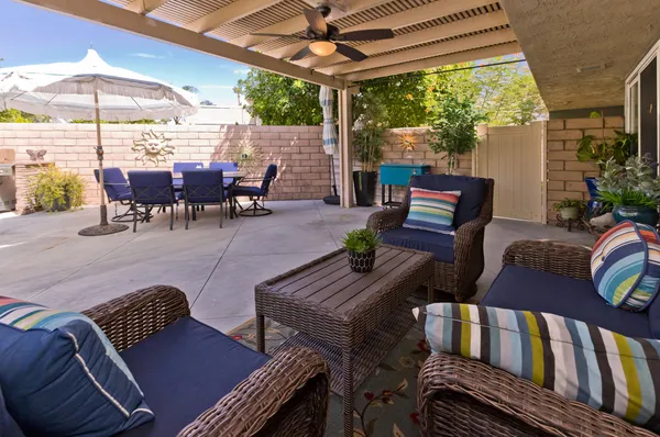 a backyard of a house with table and chairs plants and large trees