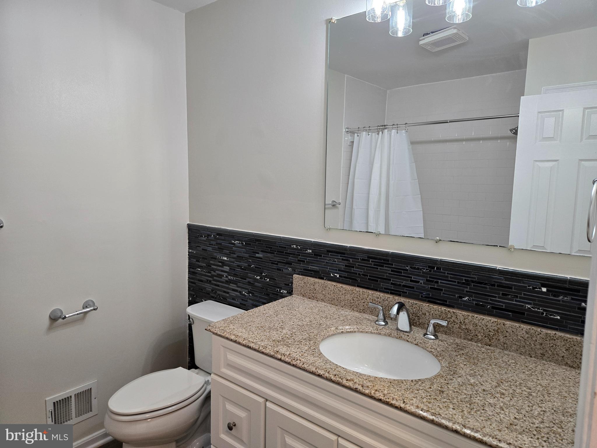 341 South 26th Street, Unit A Purcellville, VA 20132 - Photo 21 of 33 a bathroom with a granite countertop sink a mirror and a toilet
