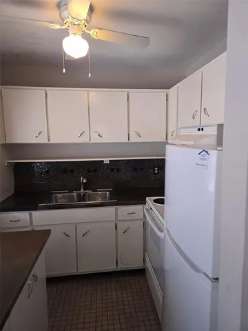 a kitchen with granite countertop white cabinets and white appliances