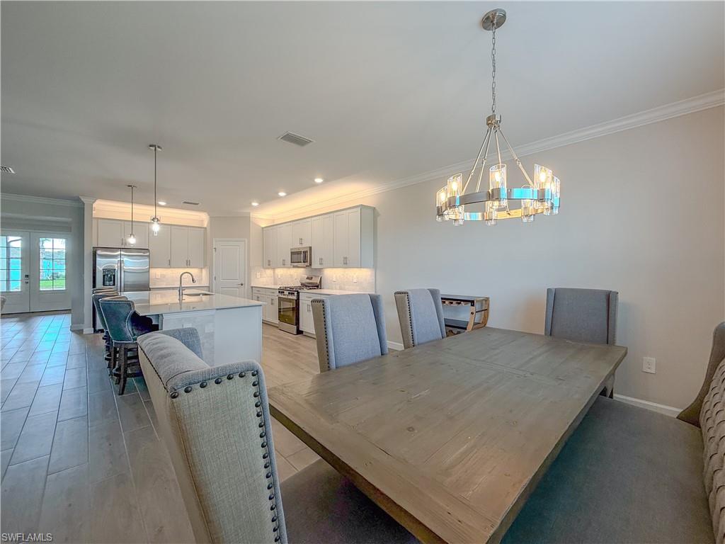 20489 Verawood Loop Estero, FL 33928 - Photo 11 of 50 Dining room featuring crown molding, a chandelier, recessed lighting, french doors, and light wood-style floors