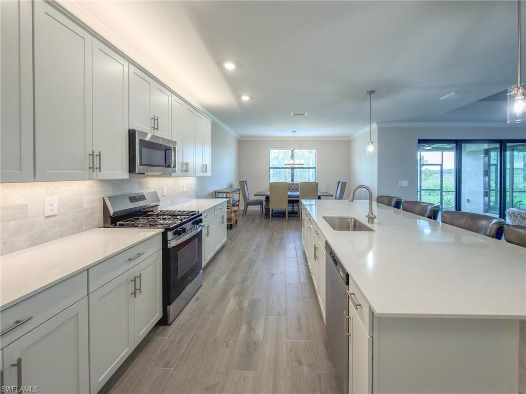 20489 Verawood Loop Estero, FL 33928 - Photo 14 of 50 Kitchen with stainless steel appliances, a large island with sink, a breakfast bar, light wood-style flooring, and ornamental molding