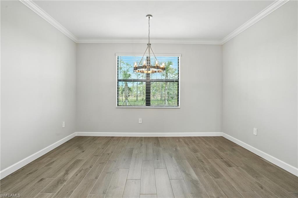 20489 Verawood Loop Estero, FL 33928 - Photo 19 of 50 Unfurnished dining area featuring wood finished floors, crown molding, and a chandelier