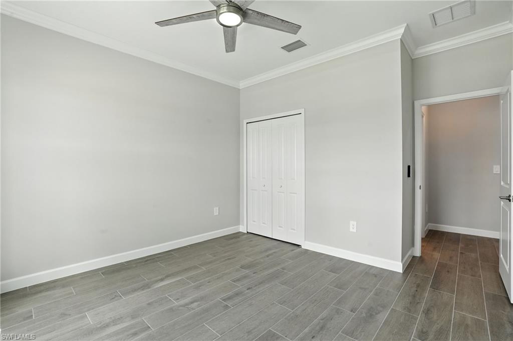 20489 Verawood Loop Estero, FL 33928 - Photo 20 of 50 Unfurnished bedroom featuring crown molding, wood finish floors, a closet, and a ceiling fan