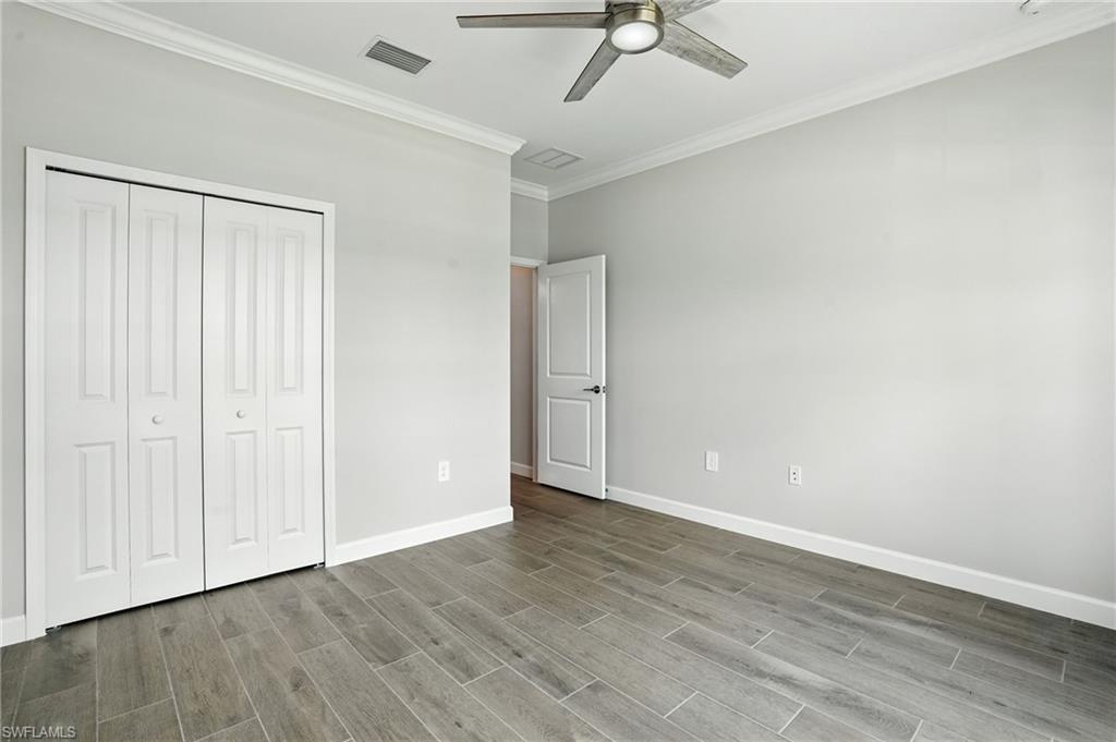 20489 Verawood Loop Estero, FL 33928 - Photo 21 of 50 Unfurnished bedroom with ornamental molding, a ceiling fan, a closet, and wood finished floors