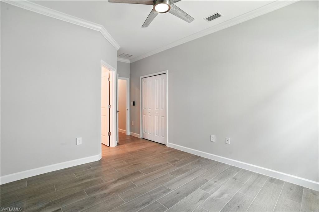 20489 Verawood Loop Estero, FL 33928 - Photo 24 of 50 Unfurnished bedroom featuring light wood-style floors, ornamental molding, ceiling fan, and a closet