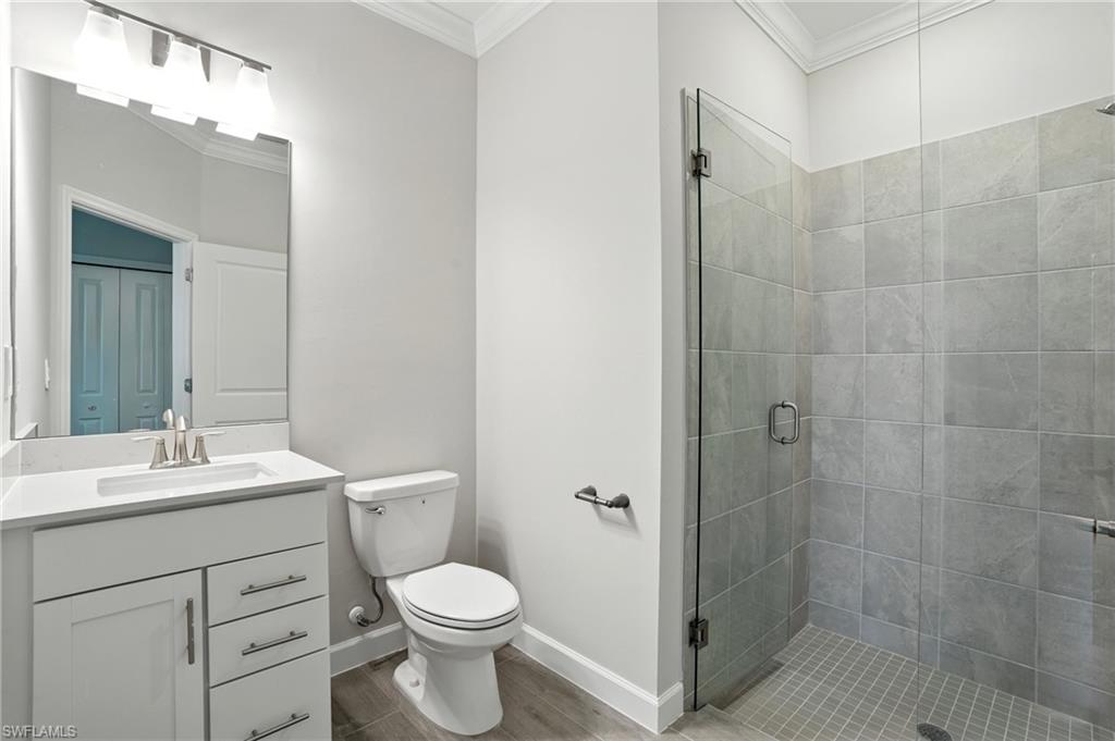 20489 Verawood Loop Estero, FL 33928 - Photo 25 of 50 Bathroom featuring a shower stall, vanity, ornamental molding, and light wood-style flooring