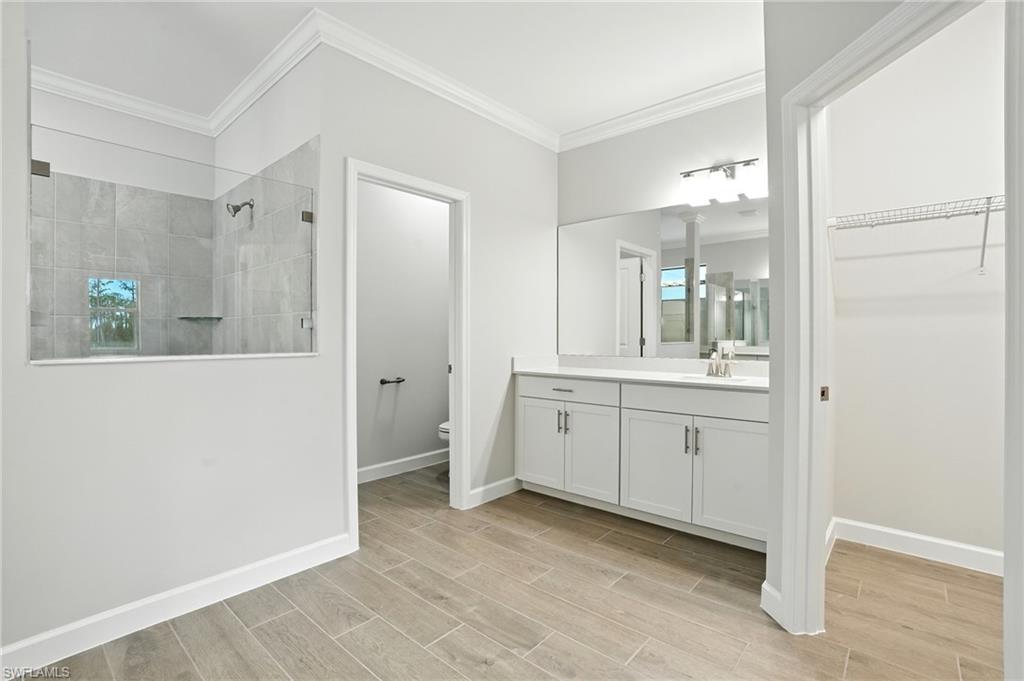 20489 Verawood Loop Estero, FL 33928 - Photo 31 of 50 Bathroom featuring a walk in shower, vanity, crown molding, wood tiled floors, and a closet