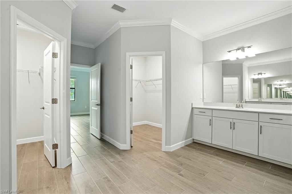 20489 Verawood Loop Estero, FL 33928 - Photo 33 of 50 Bathroom featuring a walk in closet, ornamental molding, vanity, and light wood-type flooring