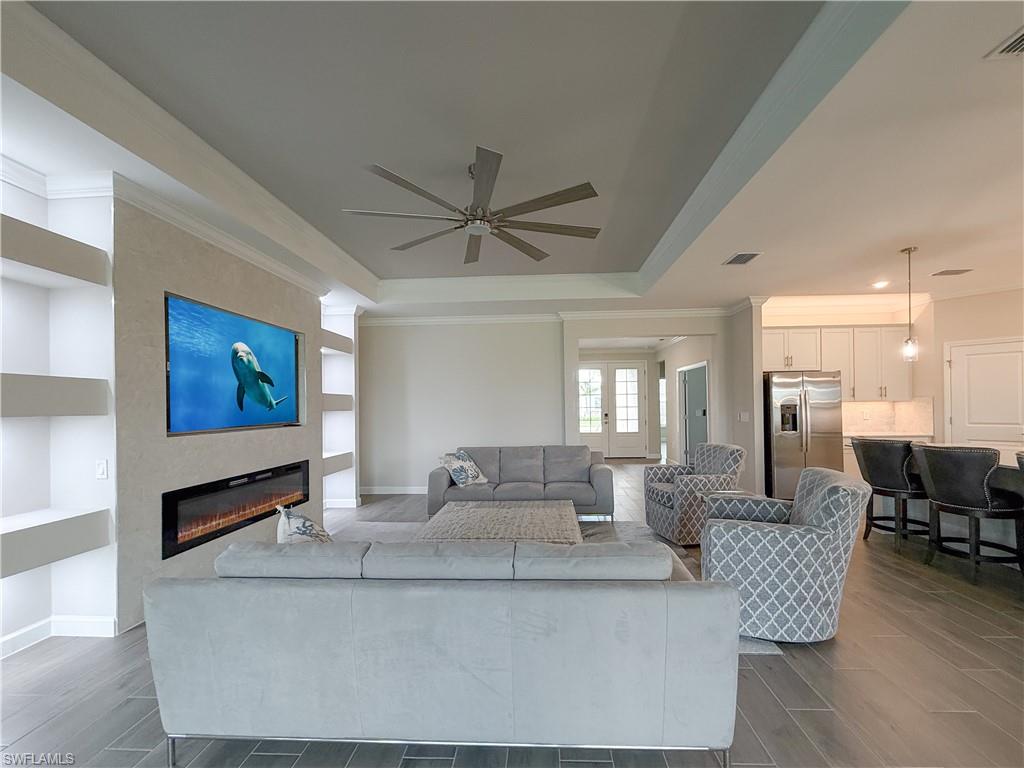 20489 Verawood Loop Estero, FL 33928 - Photo 6 of 50 Living area featuring ornamental molding, wood finish floors, a fireplace, ceiling fan, and a raised ceiling