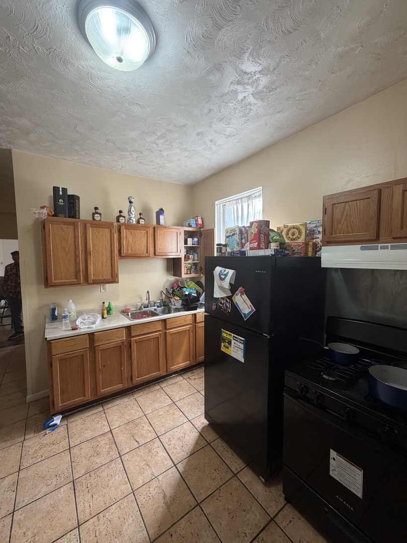 7316 South Lowe Avenue Chicago, IL 60621 - Photo 13 of 16 a kitchen with granite countertop a refrigerator and a stove top oven