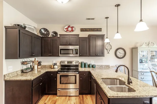 a kitchen with granite countertop a sink a stove and a wooden cabinets