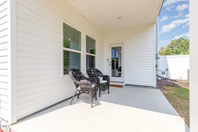 a patio with table and chairs and potted plants