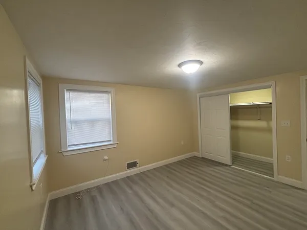 an empty room with wooden floor and windows