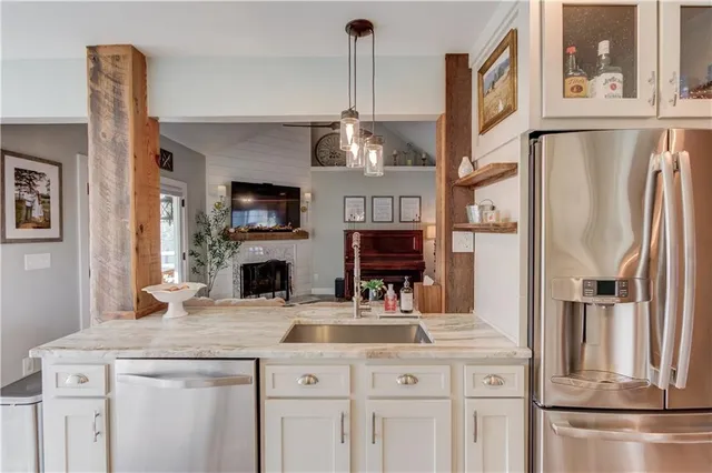 a kitchen with stainless steel appliances kitchen island granite countertop a refrigerator a stove and a sink with wooden floor