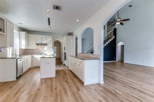 a living room with kitchen island granite countertop wooden floors and a view of living room