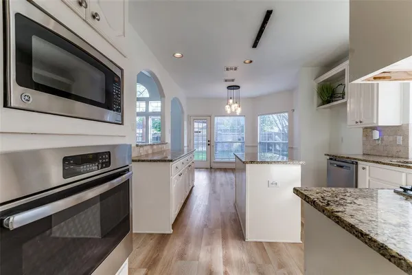 a kitchen with stainless steel appliances kitchen island granite countertop a stove and a microwave