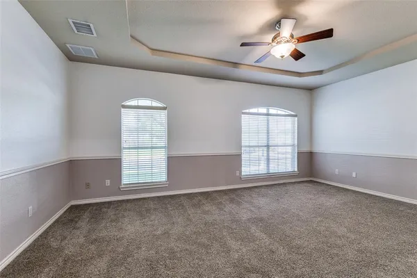 an empty room with windows and ceiling fan