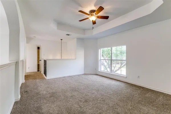 an empty room with windows and a chandelier fan