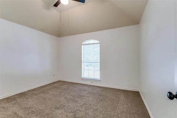 an empty room with a chandelier fan and windows