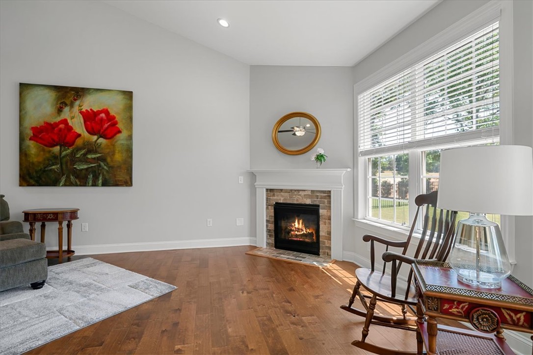 21 Barron Glenn Way Anderson, SC 29621 - Photo 6 of 48 Warm and inviting, this living room features a charming fireplace and lustrous hardwood flooring, ideal for cozy gatherings.