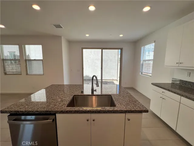 a kitchen with granite countertop a sink a counter top space cabinets and stainless steel appliances