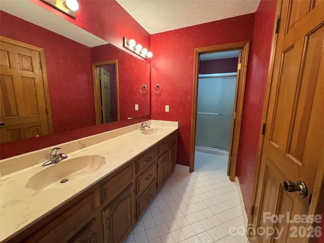 a spacious bathroom with a double vanity sink a mirror and a shower