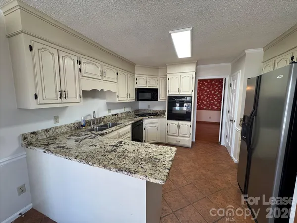 a kitchen with stainless steel appliances granite countertop a sink refrigerator and microwave